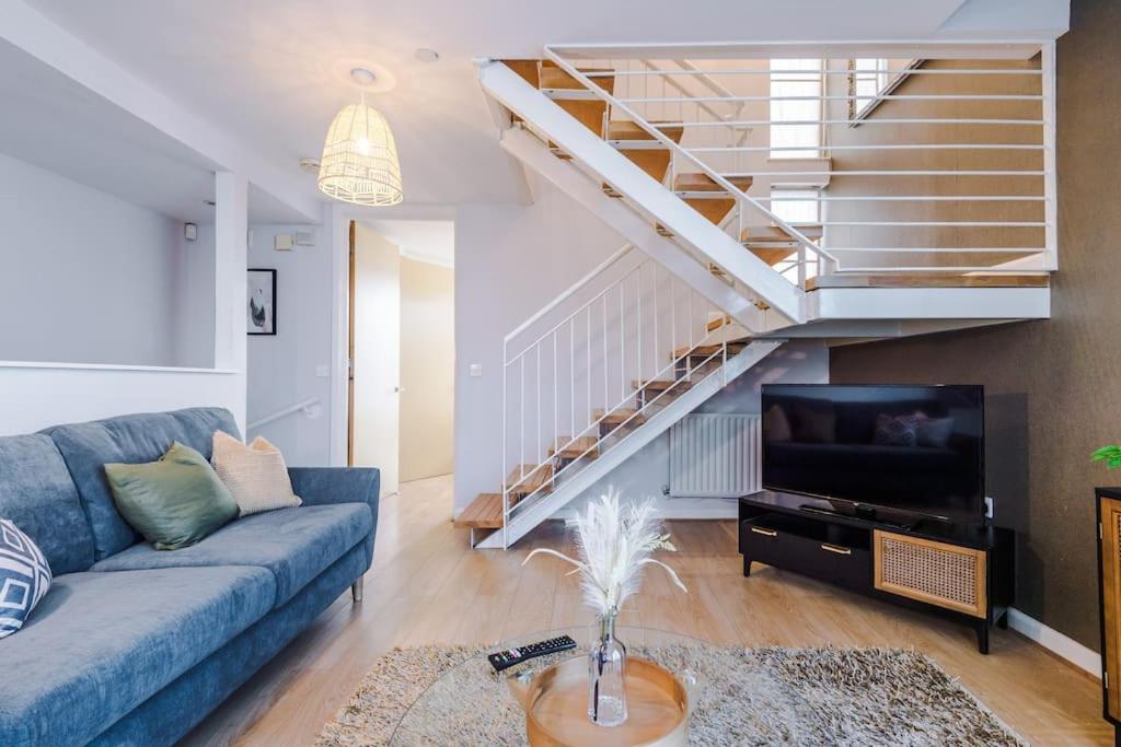 a living room with a blue couch and a staircase at Tranquil 3 Bedroom Manchester Retreat With Parking in Manchester