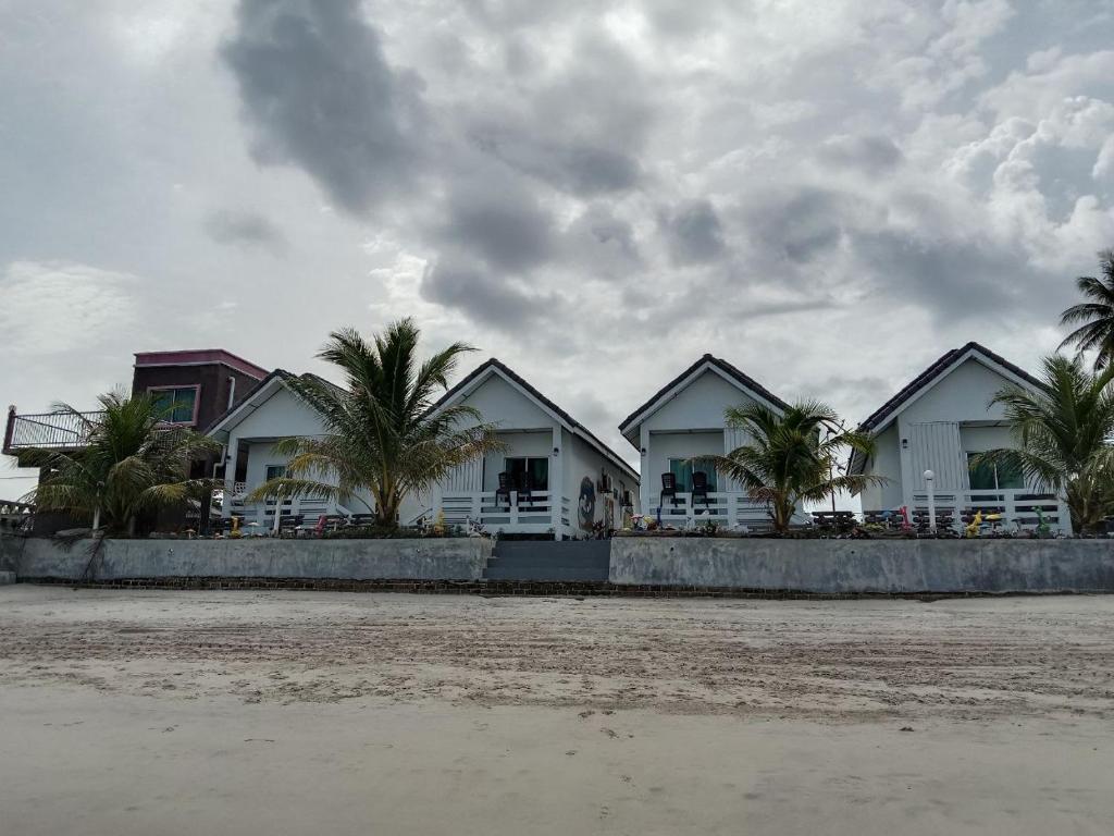 uma fila de casas na praia com palmeiras em Langkawi Primrose Seaview em Tanjung Rhu