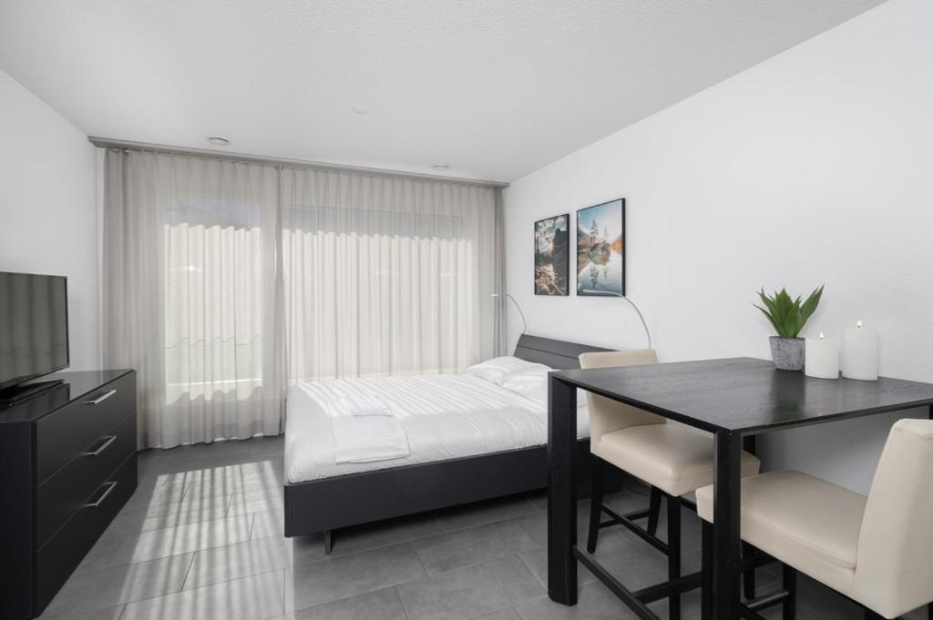 een slaapkamer met een bed, een bureau en een tafel bij Studio NATASCHA Interlaken in Interlaken