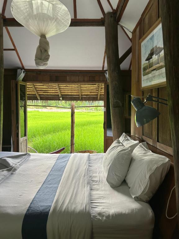 a bed in a room with a view of a field at Buzzas @ Pai Chan in Pai