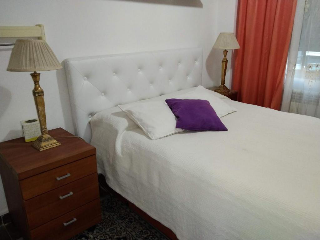 a bedroom with a white bed with a purple pillow on it at Habitaciones individuales en apartamento turístico in Madrid