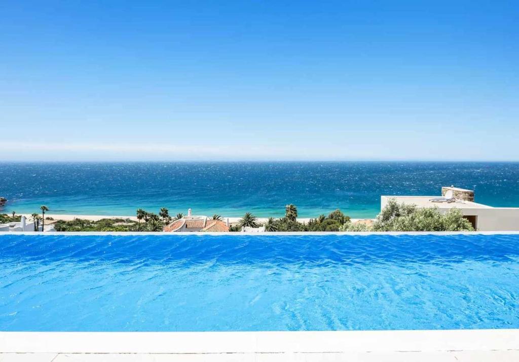 una gran piscina con el océano en el fondo en LUJOSAVILLA PISCINA 25 METROS SUIT 60m2 SPA SAUNA, en Zahara de los Atunes