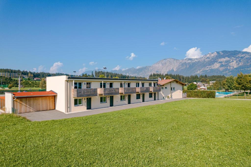 a building with a large yard with mountains in the background at Natur Residenz Bad Häring in Bad Häring