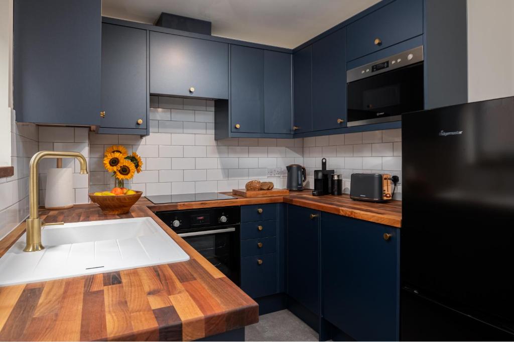 a kitchen with navy blue cabinets and a sink at 2 Bedroom City Centre Apartment, Sleeps up to 6 Guests, Free Parking in Southampton