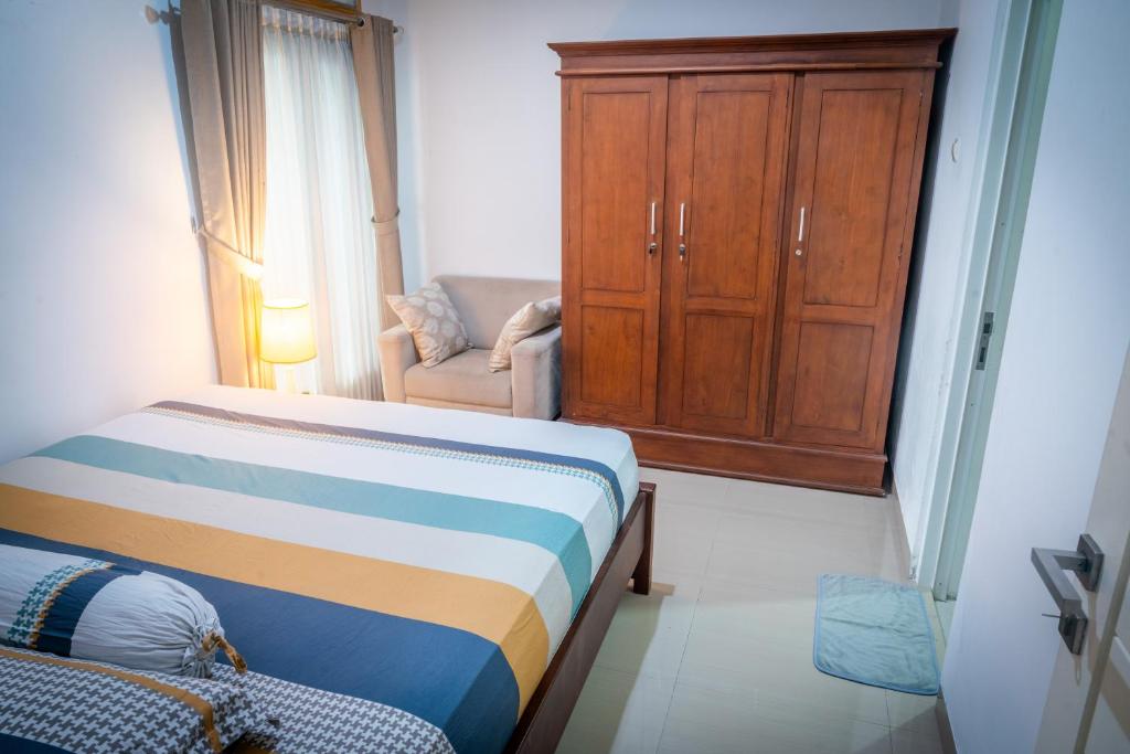 ein Schlafzimmer mit einem Bett, einem Schrank und einem Stuhl in der Unterkunft Cozy room only 20 minutes from the city center! in Ngaglik