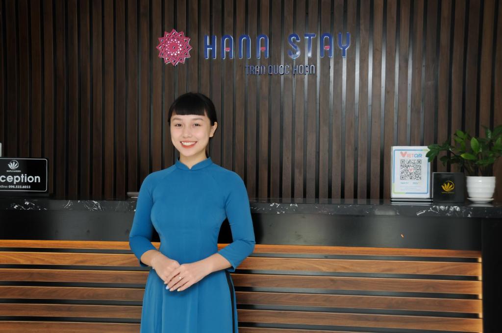 Uma mulher de vestido azul em frente a um banco. em Hana Stay Trần Quốc Hoàn em Hanói