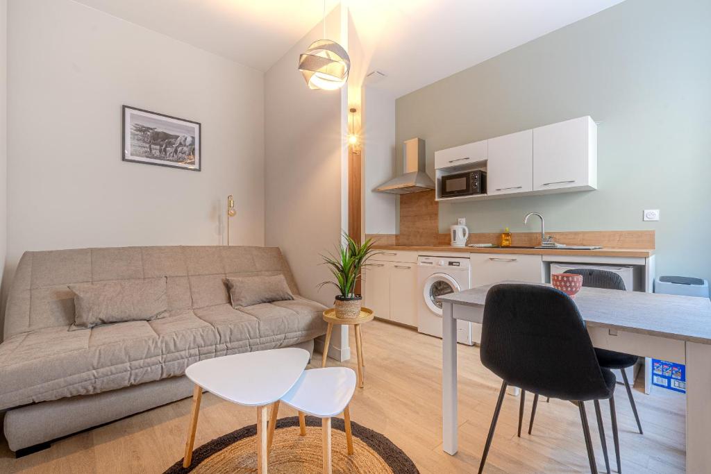 ein Wohnzimmer mit einem Sofa, einem Tisch und Stühlen in der Unterkunft studio banc léger cœur de ville in Limoges