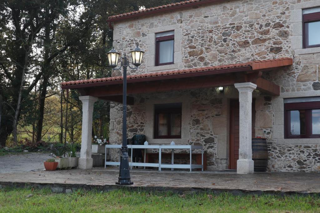 une maison en pierre avec un éclairage de rue devant elle dans l'établissement Casa de piedra, A Lameira, à A Coruña