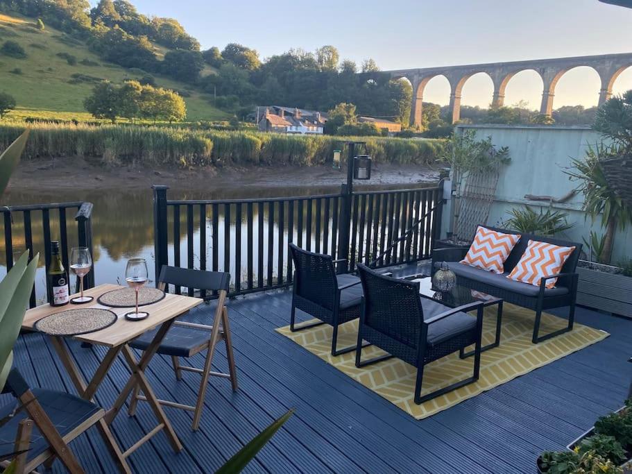 um deque com uma mesa e cadeiras, um sofá, uma mesa e cadeiras em The Waterbaby em Calstock