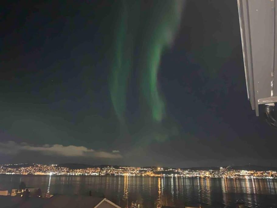 an aurora in the sky over the water at night at Cozy home. Fantastic view and parking in Tromsø