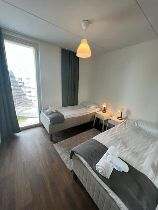 a bedroom with two beds and a large window at Kotimaailma - Tyylikäs kaksio keskustan tuntumassa in Helsinki