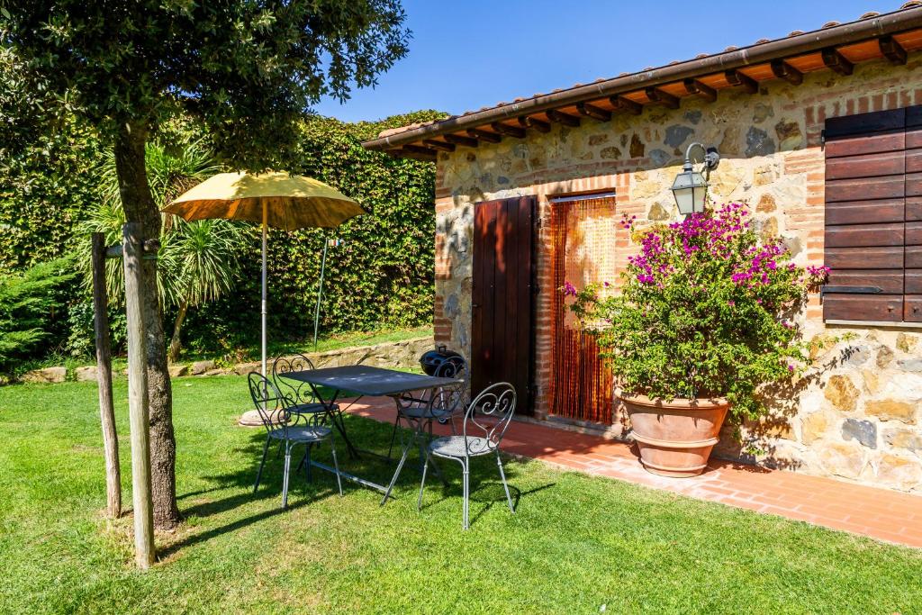 una mesa, sillas y una sombrilla en un patio en Il Cancellone - Coccinella, en Montiano