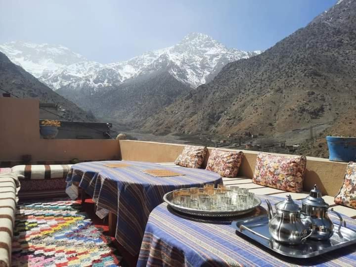 a balcony with two tables and a view of mountains at Gite Atlas Toubkal in Imlil