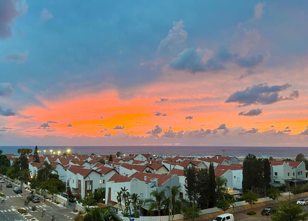 a sunset over a city with houses and a parking lot at Beachfront Studio, fully equipped in Netanya