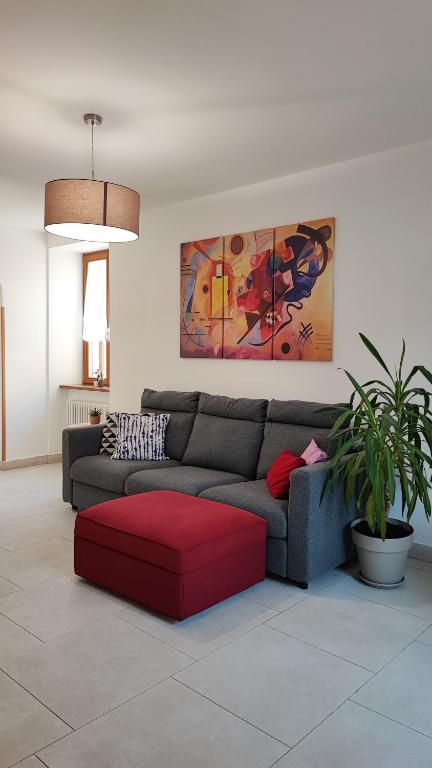 uma sala de estar com um sofá e um repousa-pés vermelhos em BLA BLA in centro em Levico Terme