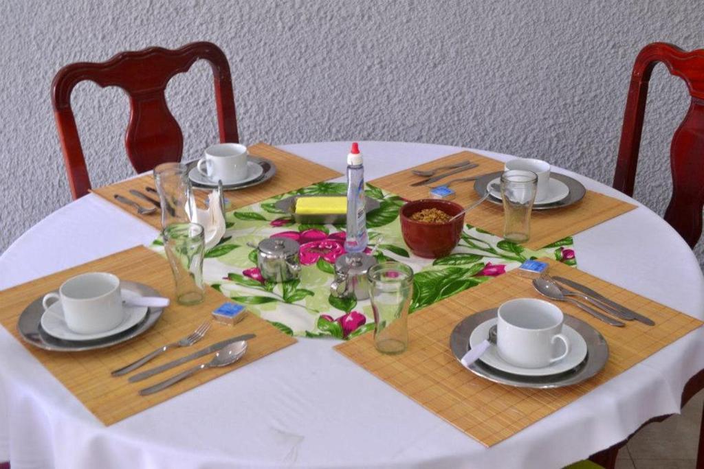 una mesa con un mantel blanco con un juego de mesa con cubiertos en Pousada Vó Irene, en Itacuruçá