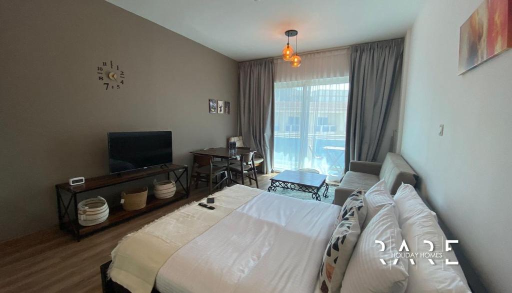 a bedroom with a large bed and a television at RARE Holiday Homes Offering Deluxe Studio near City Center Mall in RIMPZ - B2112 in Dubai