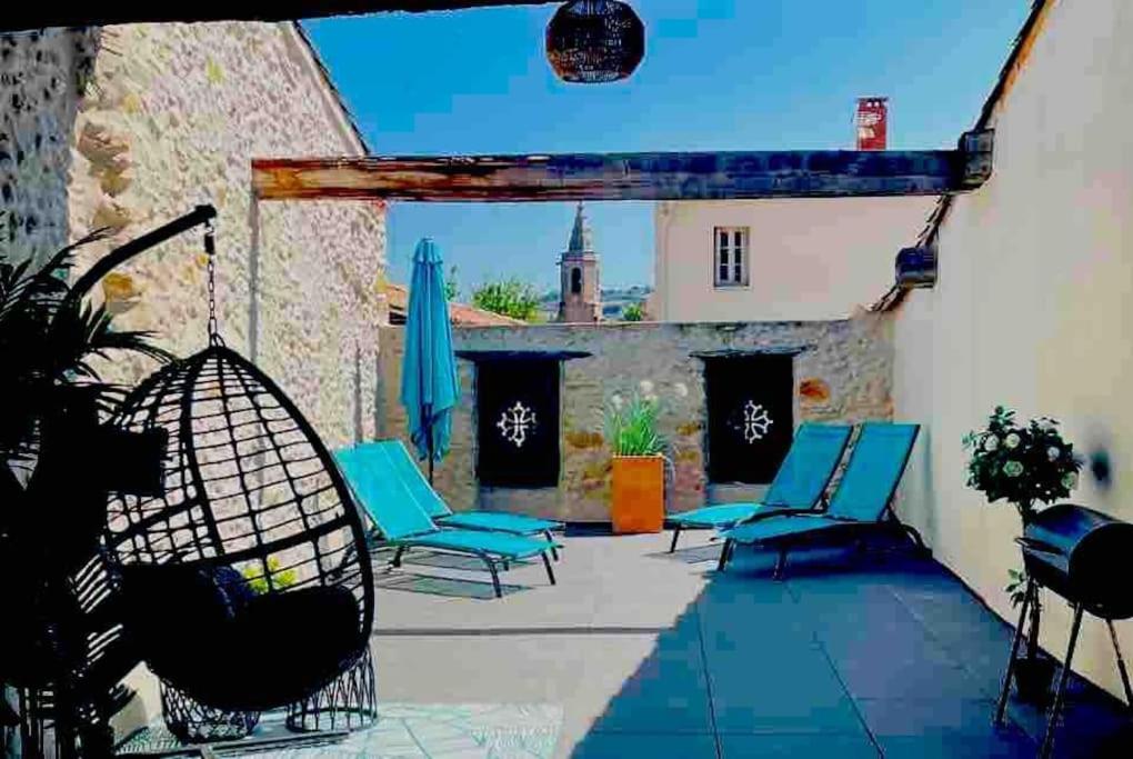 une terrasse avec des chaises bleues et un parasol dans l'établissement Elegant and Charming Townhouse with roof terrace, à Limoux