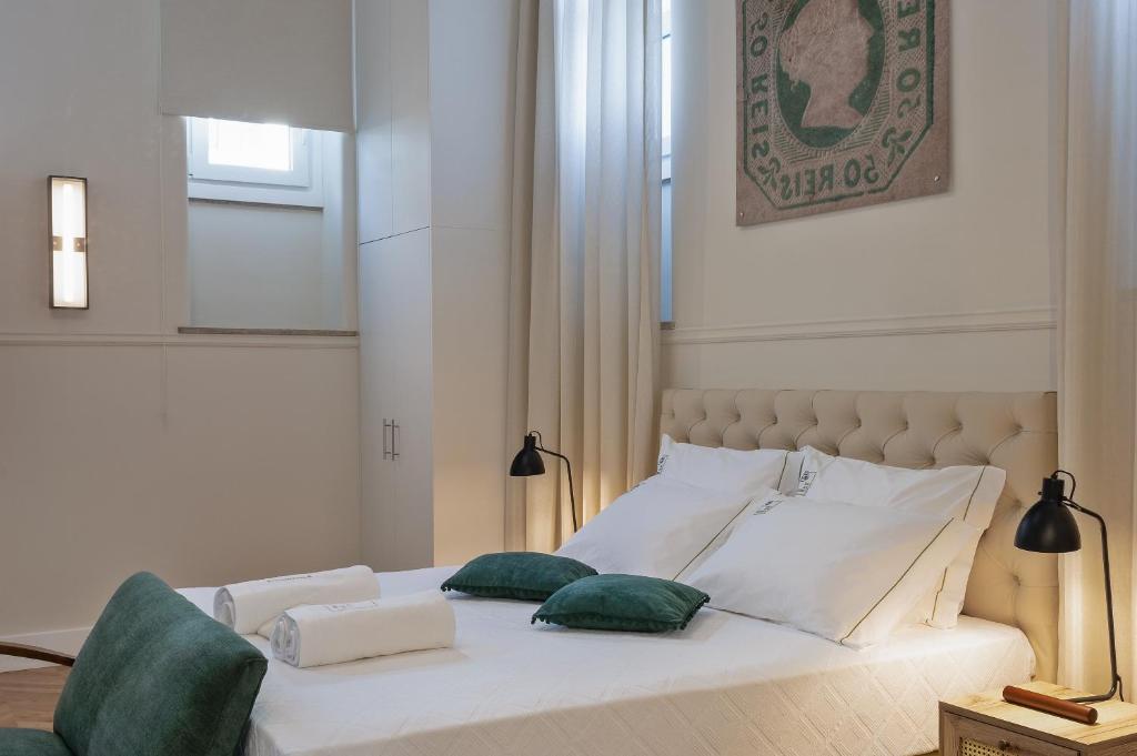 a bedroom with a white bed with two green pillows at Casa dos Correios in Vila Real