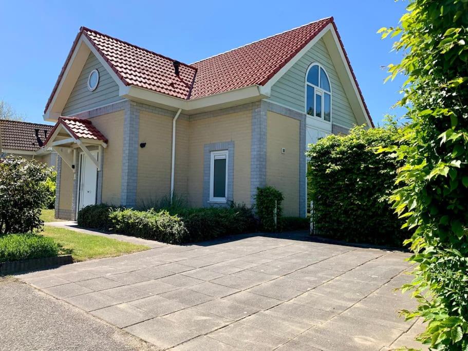a small yellow house with a red roof at Groot vakantiehuis direct aan het Zeeuwse strand in Kamperland