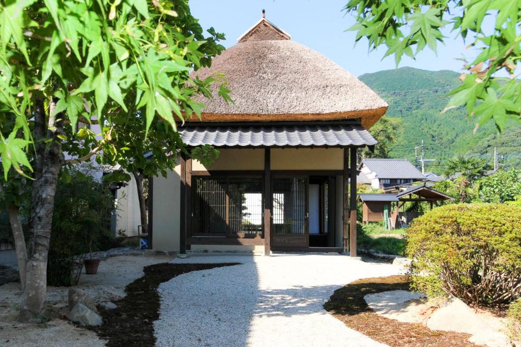 mały budynek z dachem krytym strzechą i ścieżką w obiekcie Akizuki Kayabuki Kominka w mieście Asakura