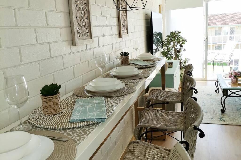 una cucina con tavolo, piatti e bicchieri da vino di Simply delightful unit close to CBD and Beach a Perth