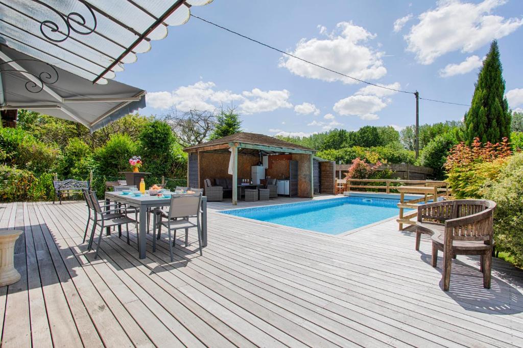 - une terrasse en bois avec une table et des chaises à côté de la piscine dans l'établissement La Longère Beauséjour, à Canapville