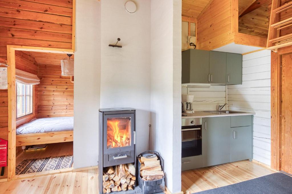 a kitchen with a fireplace in a log cabin at Pinetree Cottages Blue Cabin in Pyhäranta