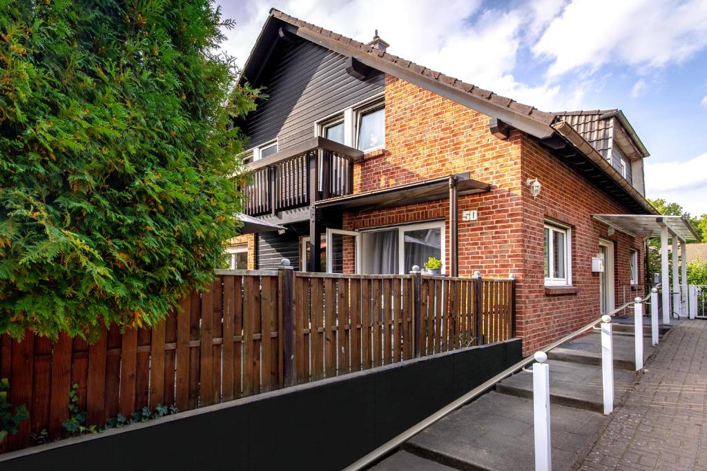 a brown brick house with a wooden fence at Pension Haus am Kohfurth in Norderstedt