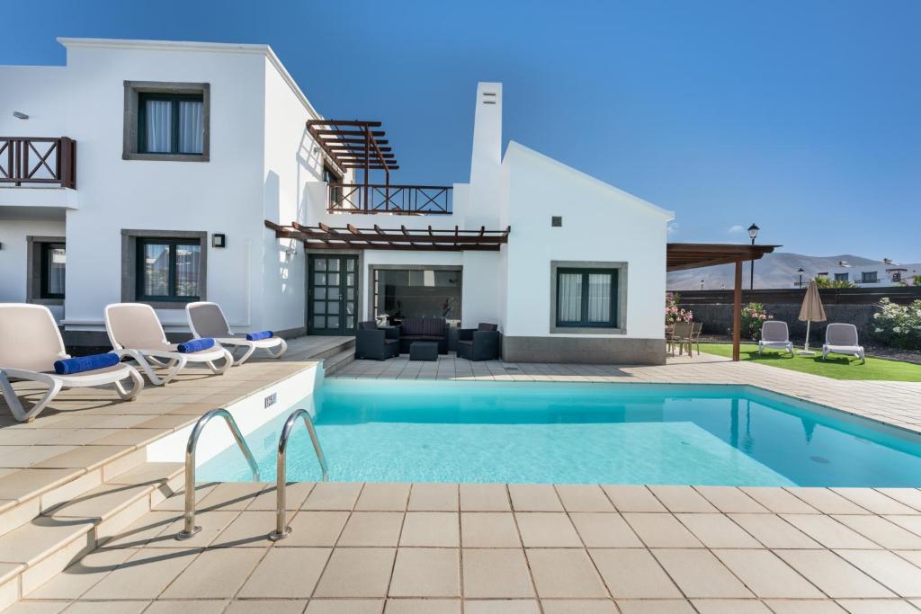 a villa with a swimming pool and a house at Camelot Holiday Homes by LIVVO in Playa Blanca