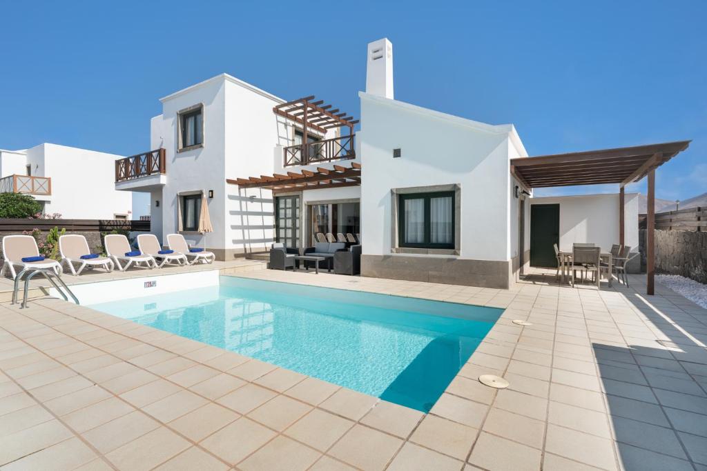 a villa with a swimming pool and a house at Villas Camelot by LIVVO in Playa Blanca