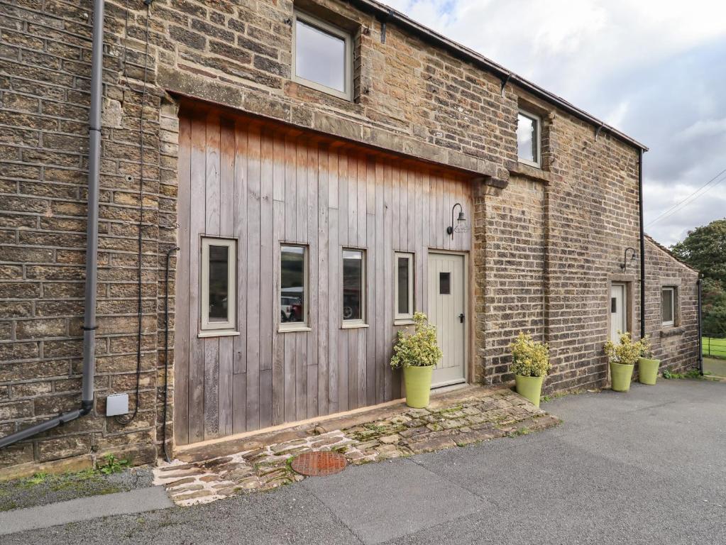 a brick building with a wooden door and two potted plants at The Cow Shed in Holmfirth