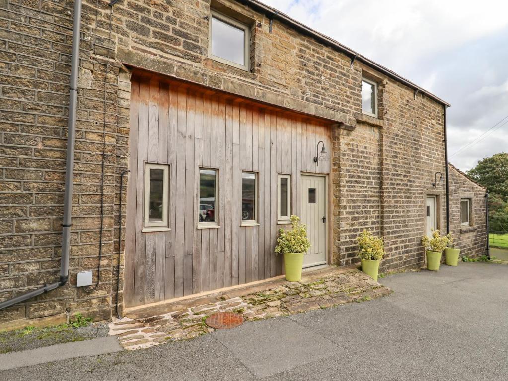 a brick building with a door and two potted plants at The Hayloft in Holmfirth