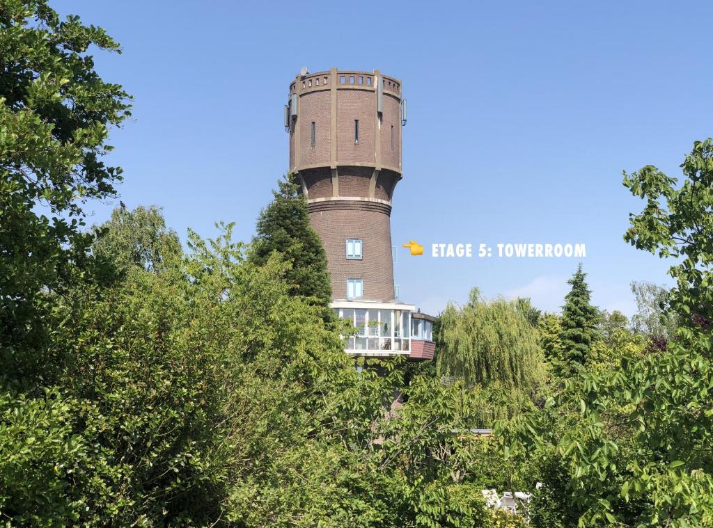 a lighthouse on top of a hill with trees at Torenkamer op de vijfde verdieping van de watertoren van Strijen in Strijen