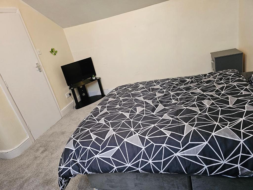 1 dormitorio con 1 cama con edredón blanco y negro en VIKKY LODGE en Birmingham