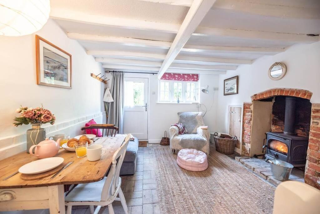 a living room with a table and a fireplace at Lilac Cottage, Wenhaston in Halesworth