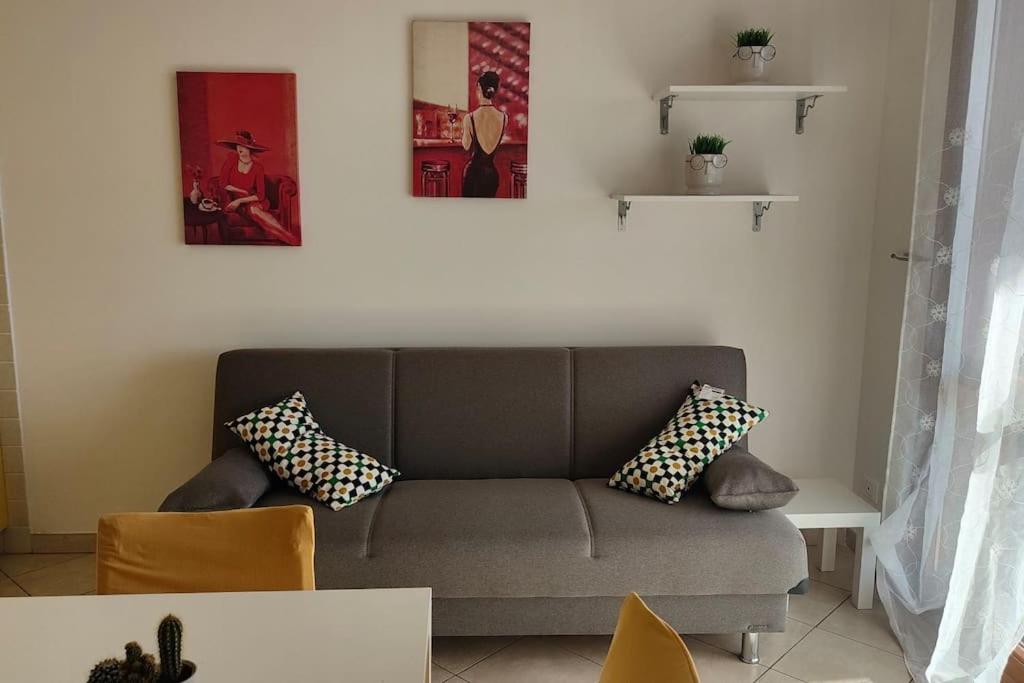 ein Wohnzimmer mit Sofa und zwei Bildern an der Wand in der Unterkunft PomeziaCity Apartment in Pomezia