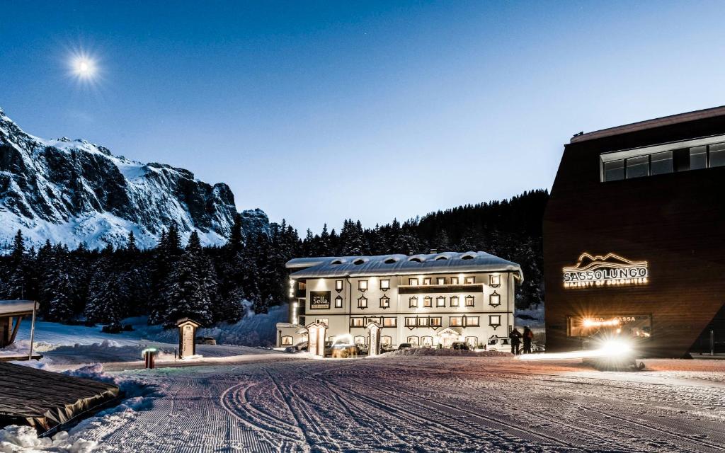 un grande edificio nella neve vicino a una montagna di Hotel Sella***s a Selva di Val Gardena