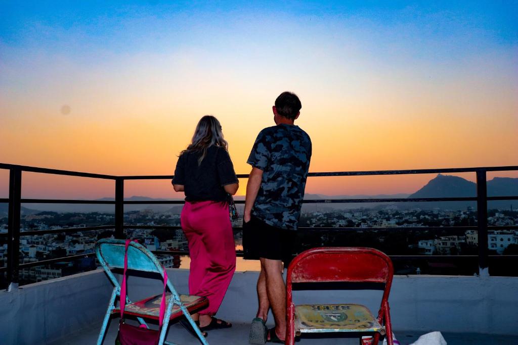 een stel dat op een dak staat te kijken naar de zonsondergang bij Bunkyard Hostel in Udaipur