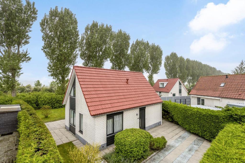 a white house with a red roof at Kustverhuur, Park Schoneveld, Stern 204 in Breskens