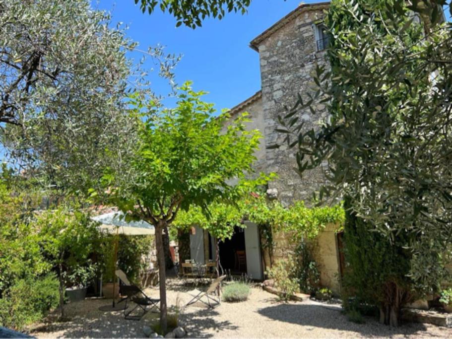 une ancienne maison en pierre avec des arbres devant elle dans l'établissement 06AW - Mas en pierre provençal rénové au calme, à Le Rouret