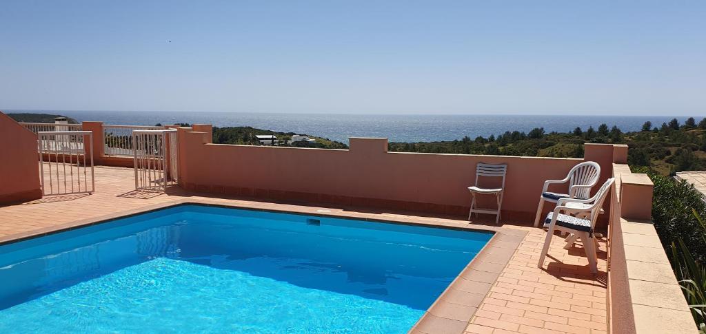 una piscina con 2 sillas y vistas al océano en Villa Cabanas beach en Budens