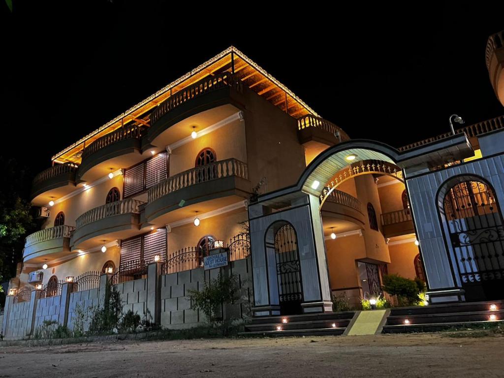 Un grand bâtiment avec des lumières allumées la nuit dans l'établissement Mikhaila Guest House, à Louxor