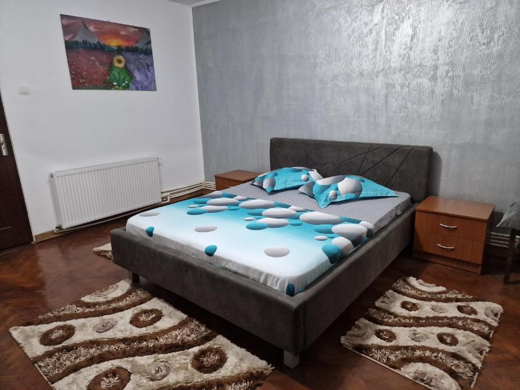 um quarto com uma cama com lençóis e almofadas azuis em GARSONIERA ÎN REGIM HOTELIER em Târgu Jiu