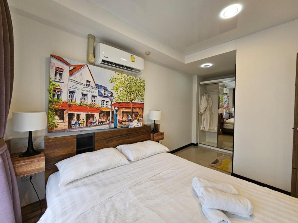 a bedroom with a large white bed with a painting on the wall at Phuket Airport Hotel at Mai Khao Beach in Ban Bo Sai Klang