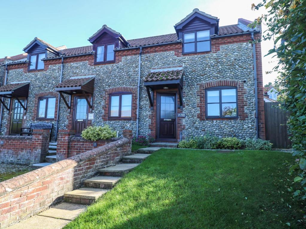 an exterior view of a brick house with a yard at Seaview Cottage in Holt