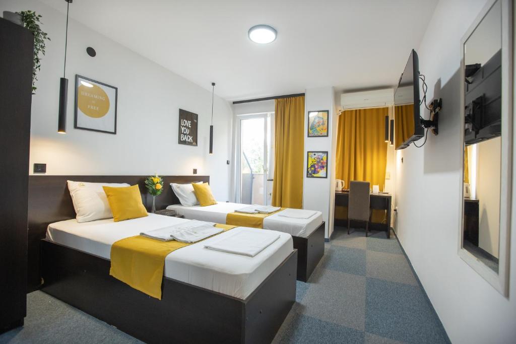 a hotel room with two beds and a tv at 4 Rooms Apartments in Niš