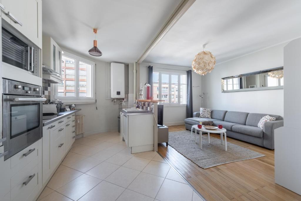 une cuisine et un salon avec un canapé et une table dans l'établissement Le Bossuet - Location moyenne durée Lyon 6ème, à Lyon