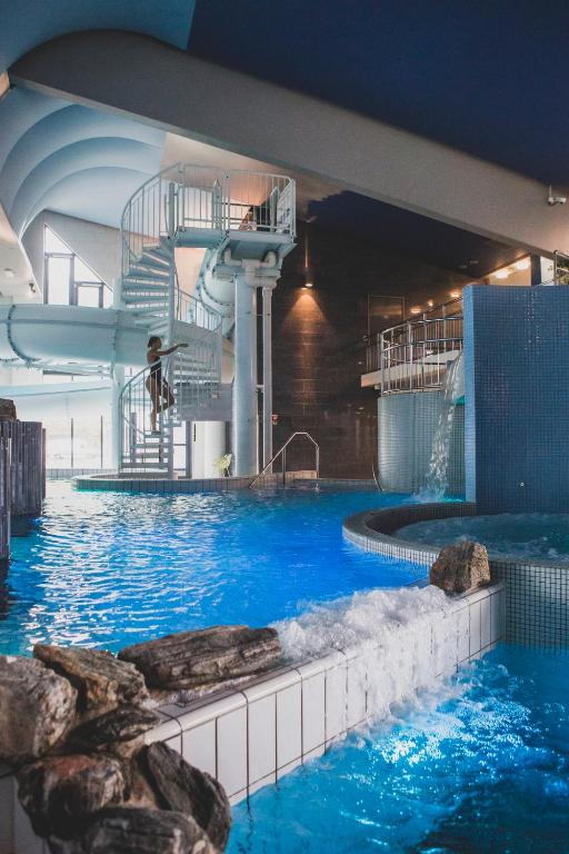 a person jumping off a water slide in a swimming pool at Levi Hotel Spa in Levi