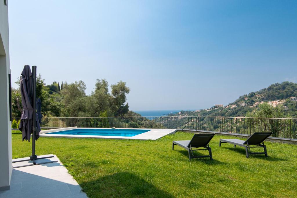 a backyard with a swimming pool and two chairs and an umbrella at Jolie maison au calme in Menton
